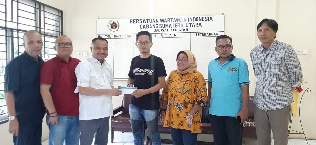 Ketua PWI Sumut, Farianda Putra Sinik, menyerahkan santunan asuransi kepada Lamhar Simaremare