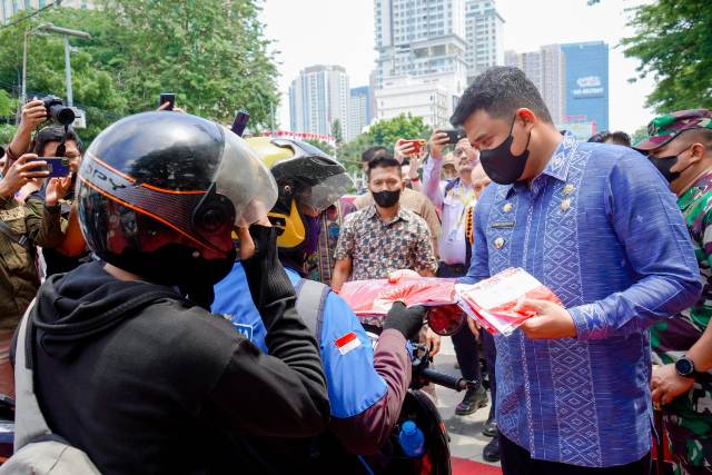Wali Kota Medan, Bobby Nasution, membagikan bendera kepada pengguna jalan di depan Balai Kota Medan