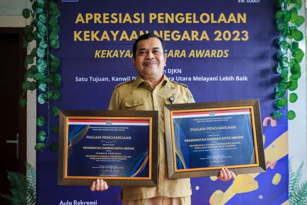 Kepala BKAD Kota Medan, Zulkarnain, memperlihatkan dua penghargaan Kekayaan Negara Award yang diterima